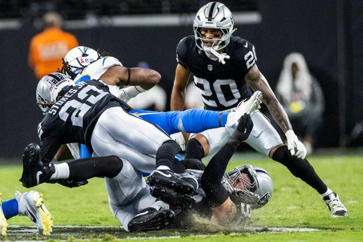 Raiders safety Isaiah Pola-Mao (20) and defensive end Maxx Crosby (98) team up to stop Los Ange ...