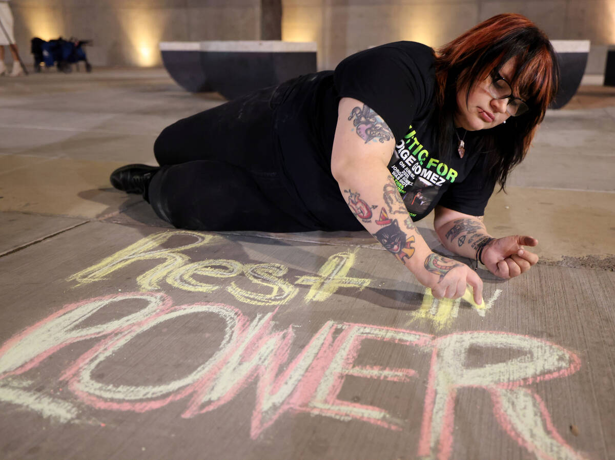 Kat Kalling draws a message in chalk during a vigil for Jorge Gomez outside the Lloyd George U. ...