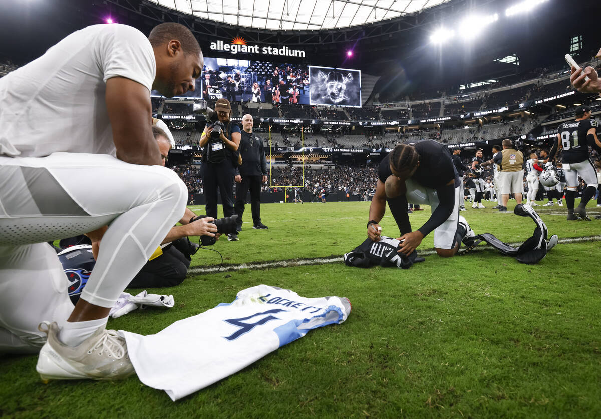 Raiders quarterback Geno Smith (7) and Tennessee Titans wide receiver Tyler Lockett (4) sign je ...