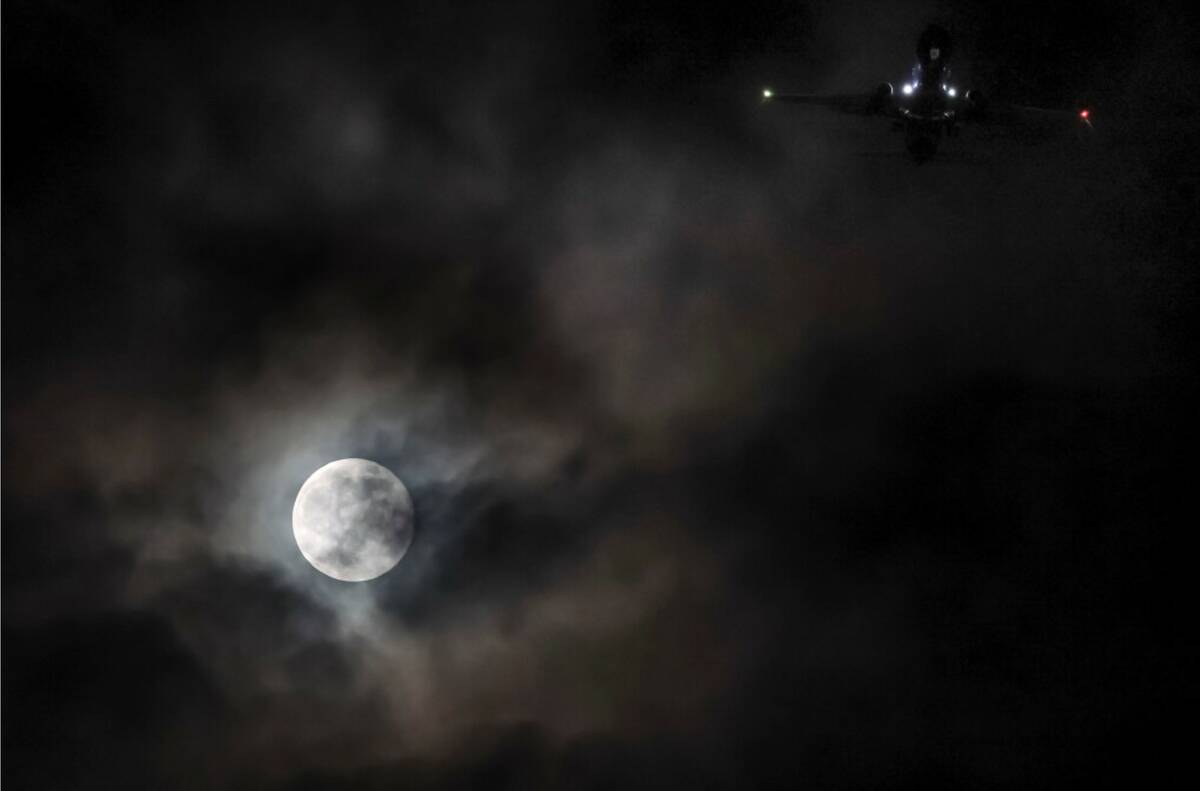 A plane passes by the Beaver supermoon as it rises over the Las Vegas Valley on Wednesday, Nov. ...