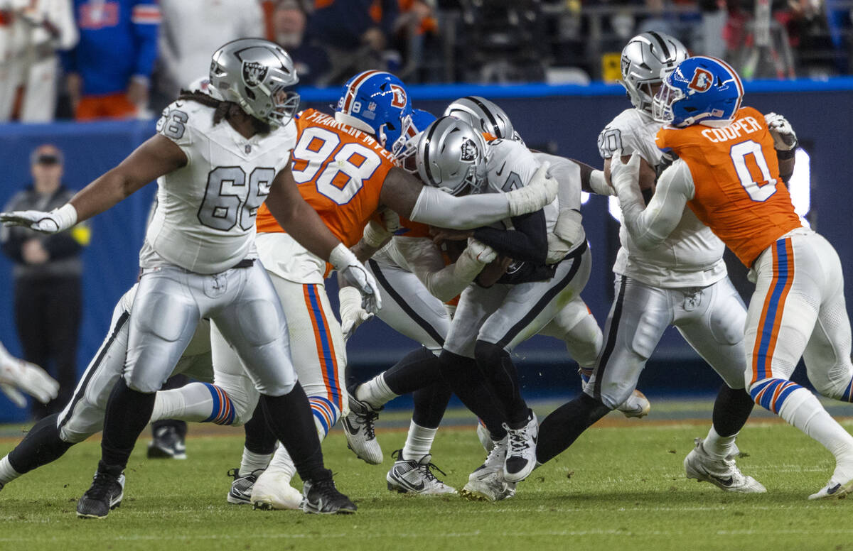 Raiders quarterback Geno Smith (7) is sacked by Denver Broncos defensive end Zach Allen (99) an ...