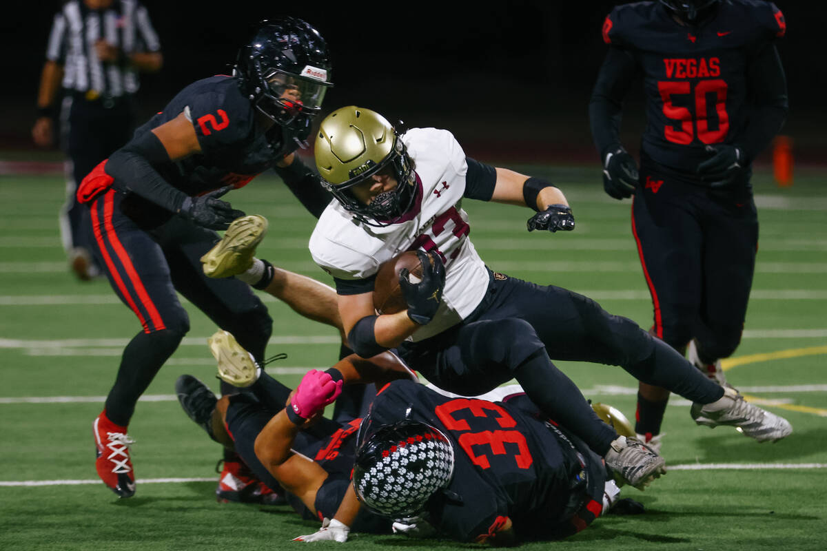 Faith Lutheran running back Justin Robbins (33) tumbles over Las Vegas defenders during the Sou ...