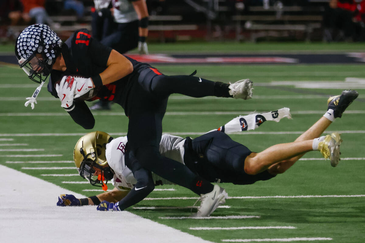 Faith Lutheran defensive back Gavin Day (1) trips up Las Vegas wide receiver Porter Wells (17) ...