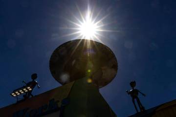 The afternoon sun light rays pierce through a metal Aliens sculpture and their craft outside of ...