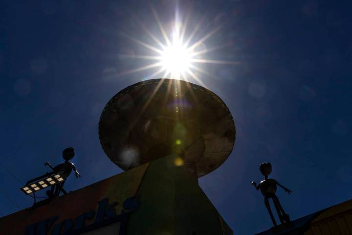 The afternoon sun light rays pierce through a metal Aliens sculpture and their craft outside of ...
