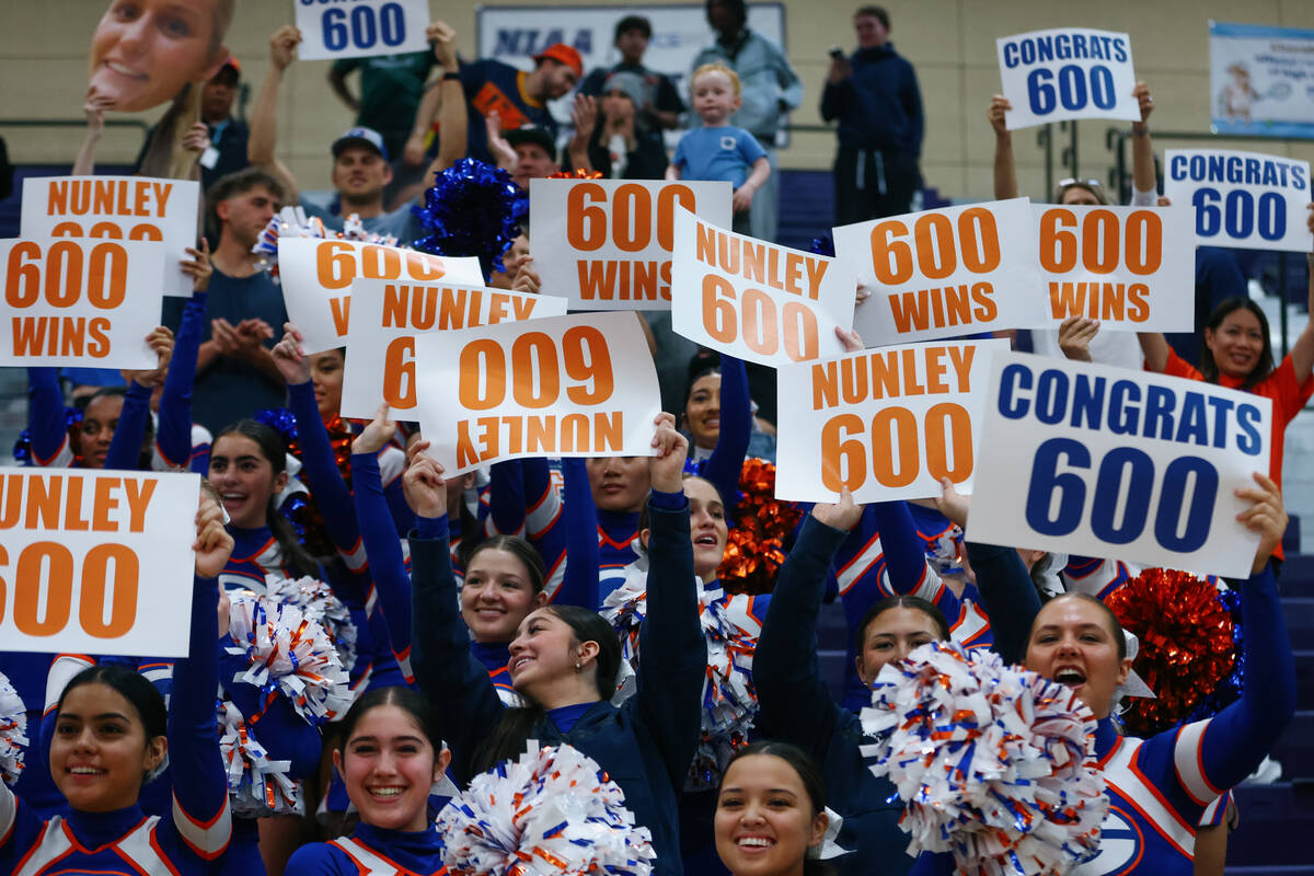 Bishop Gorman cheerleaders and fans hold up signs commemorating head coach Gregg Nunley marking ...