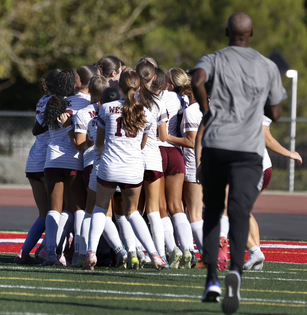 Faith Lutheran's girls soccer team head coach Carl Cort, right, joins his players as they ...