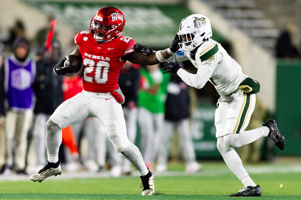 UNLV running back Jaylon Glover (20) stiff arms Colorado State Rams defensive back Lemondre Joe ...