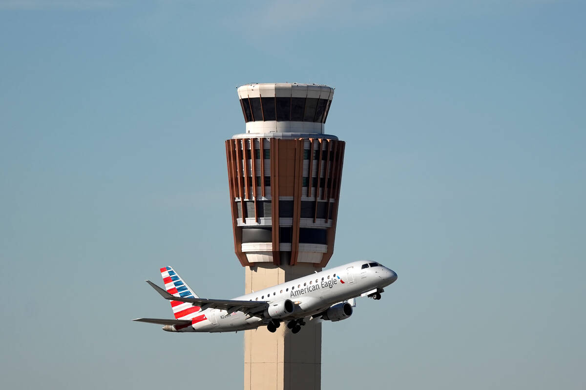 An American Airlines American Eagle jet flies past the air traffic control tower at Phoenix Sky ...