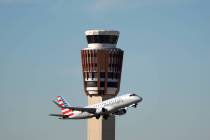 An American Airlines American Eagle jet flies past the air traffic control tower at Phoenix Sky ...
