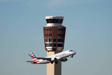An American Airlines American Eagle jet flies past the air traffic control tower at Phoenix Sky ...