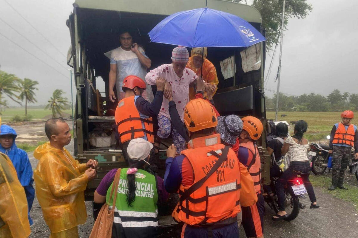 In this photo provided by the Philippine Coast Guard, rescuers evacuate residents in Sablayan, ...