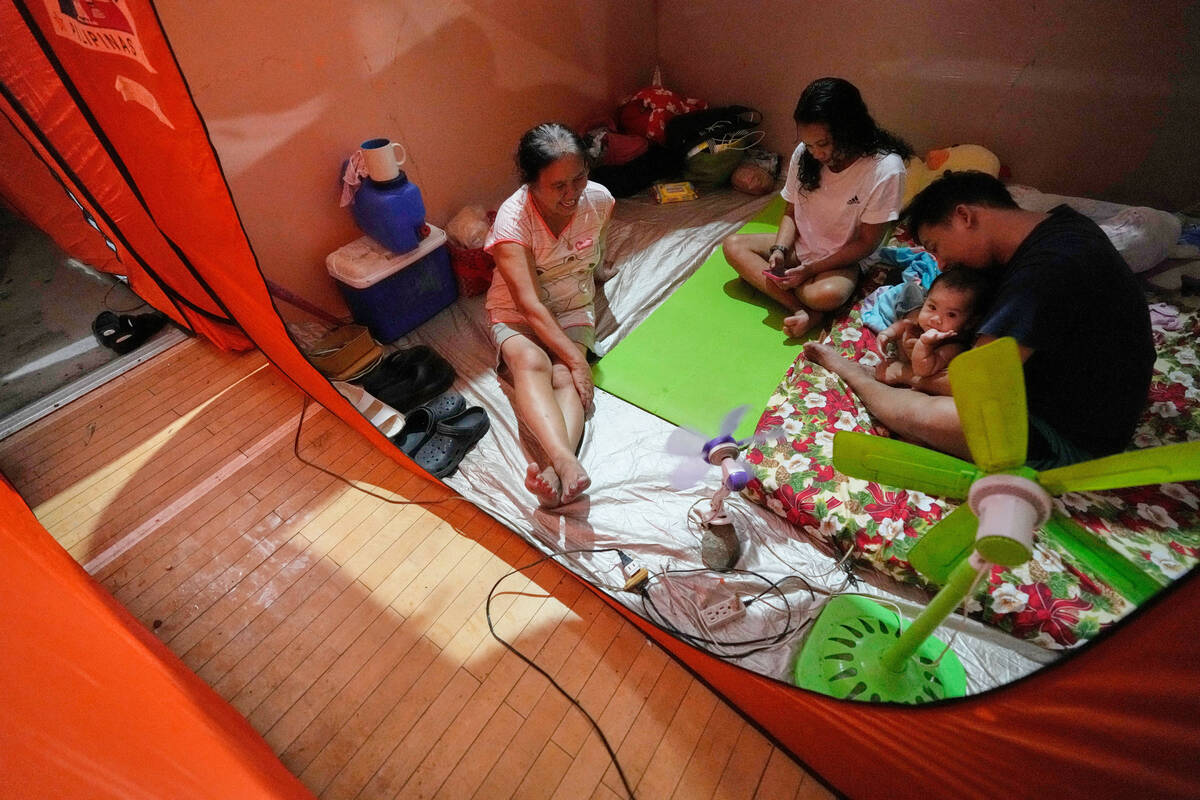 Judie Delector, right, and his family stay inside a tent at an evacuation center as Typhoon Fun ...