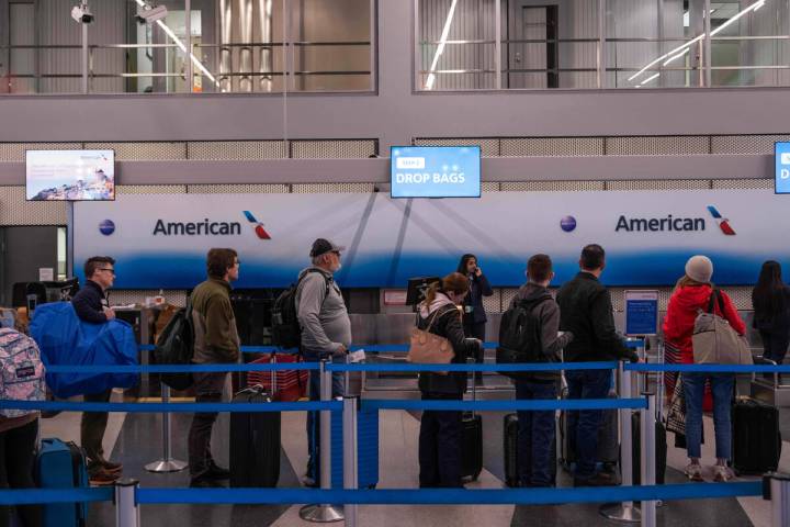 People wait in line to check in to American Airlines flights at Chicago O'Hare Internation ...