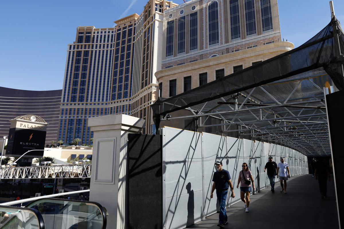 Pedestrians walk on a pedestrian bridge connecting the Palazzo to the Treasure Island hotel-cas ...