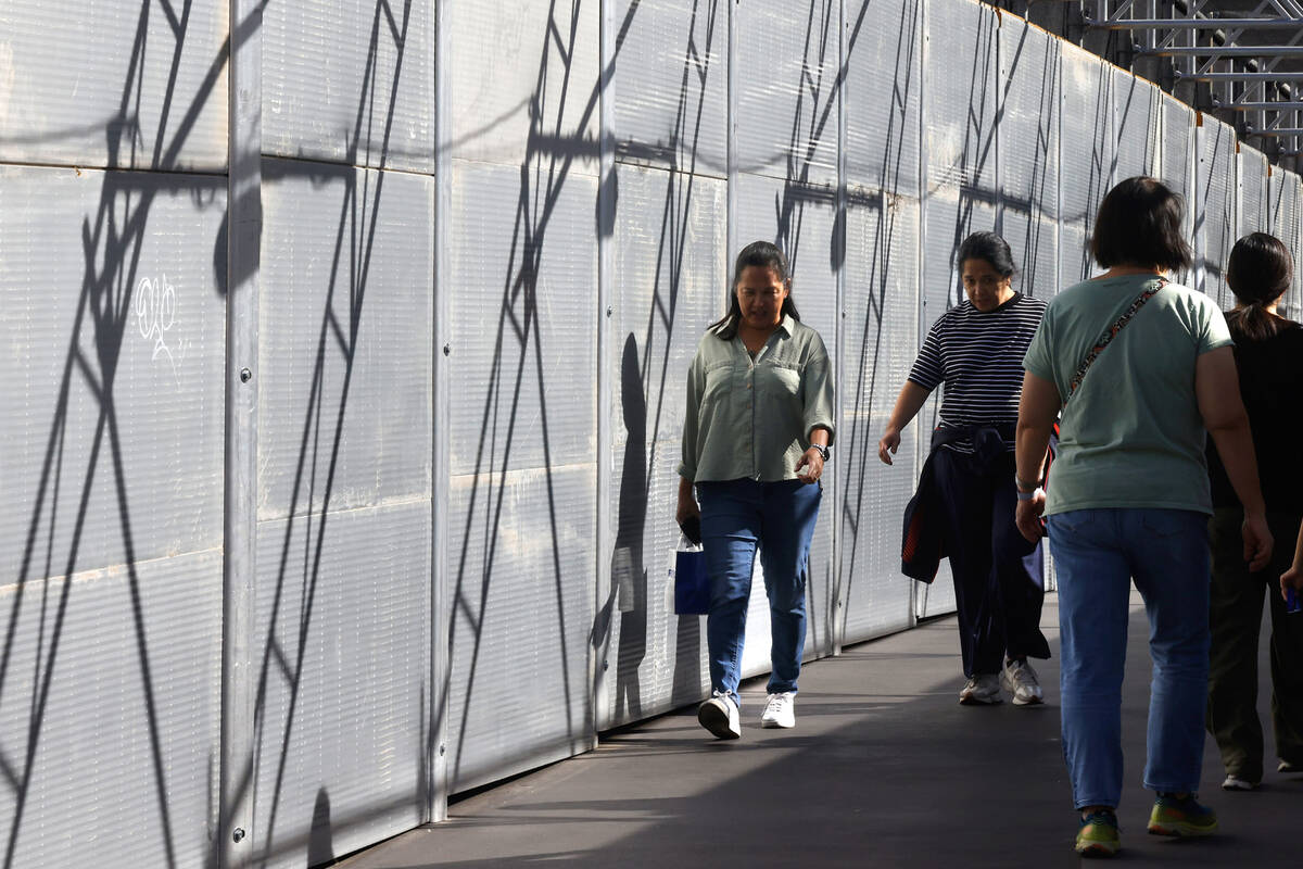 Pedestrians walk on a pedestrian bridge connecting the Palazzo to the Treasure Island hotel-cas ...