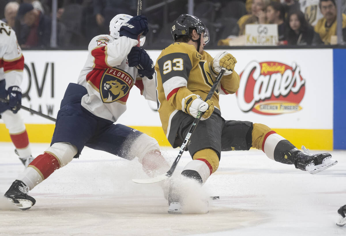 Golden Knights right wing Mitch Marner (93) gets tripped up while battling for the puck against ...