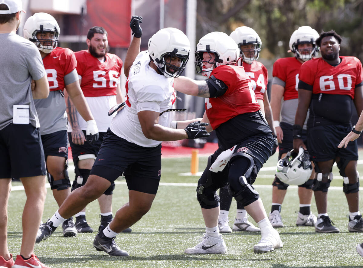 UNLV defensive line Waisale Muavesi (91) and offensive line Reid Williams (64) engage in drills ...