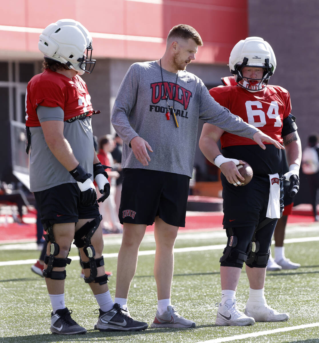 UNLV offensive lines Austin Boyd (79) and Reid Williams (64) listen to offensive line coach Mik ...