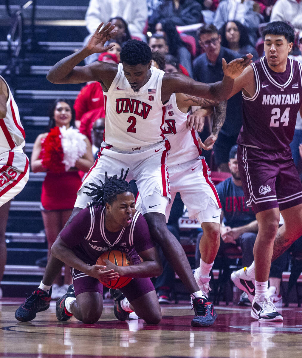 Montana Grizzlies guard Money Williams (0) falls on a loose ball with UNLV forward Kimani Hamil ...