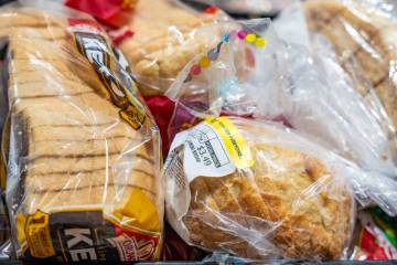 Crates of different brands of donated bread sit ready to be packed into smaller boxes for famil ...