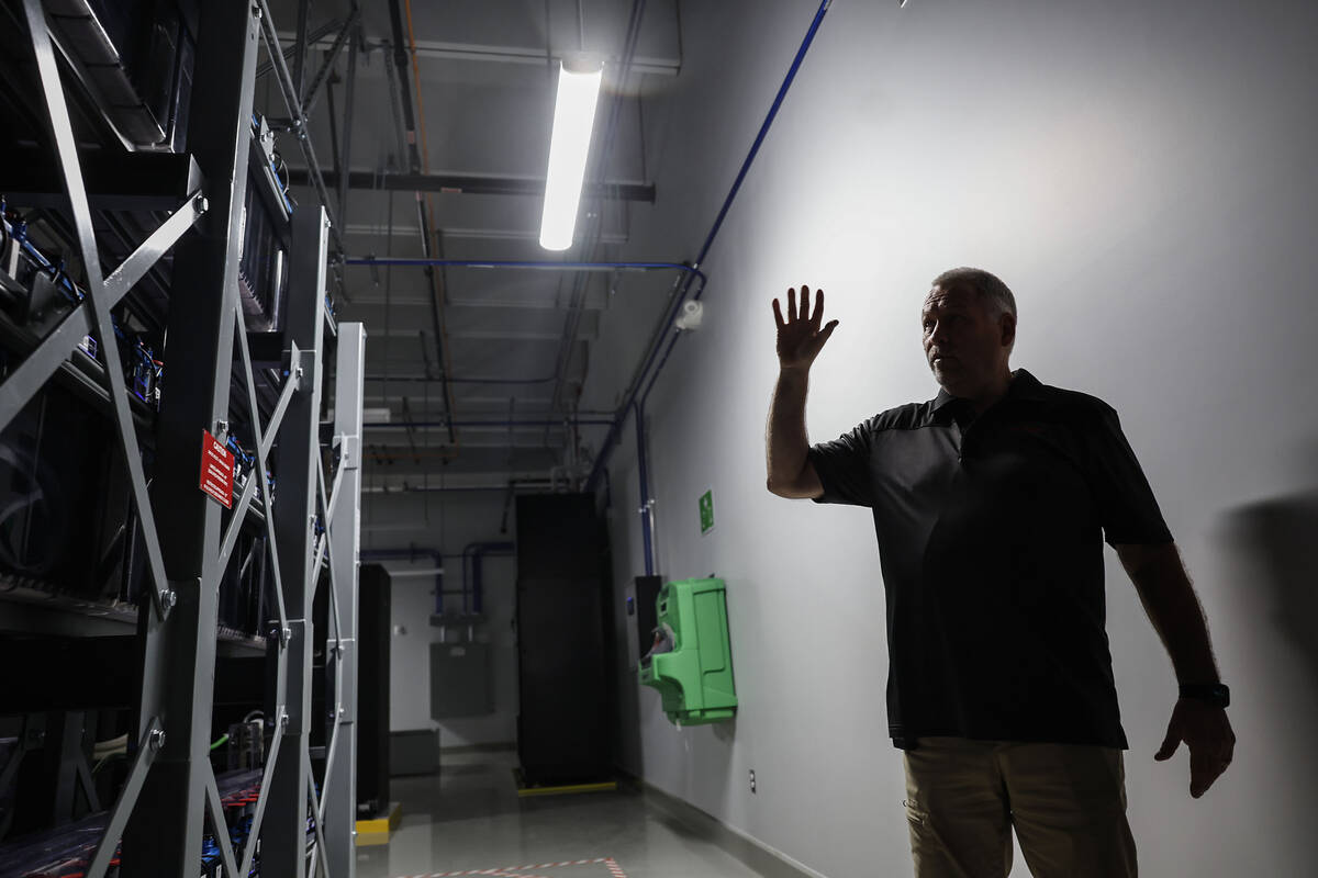 Dave Nelson, senior director of operations, points out features of rows of battery storage duri ...