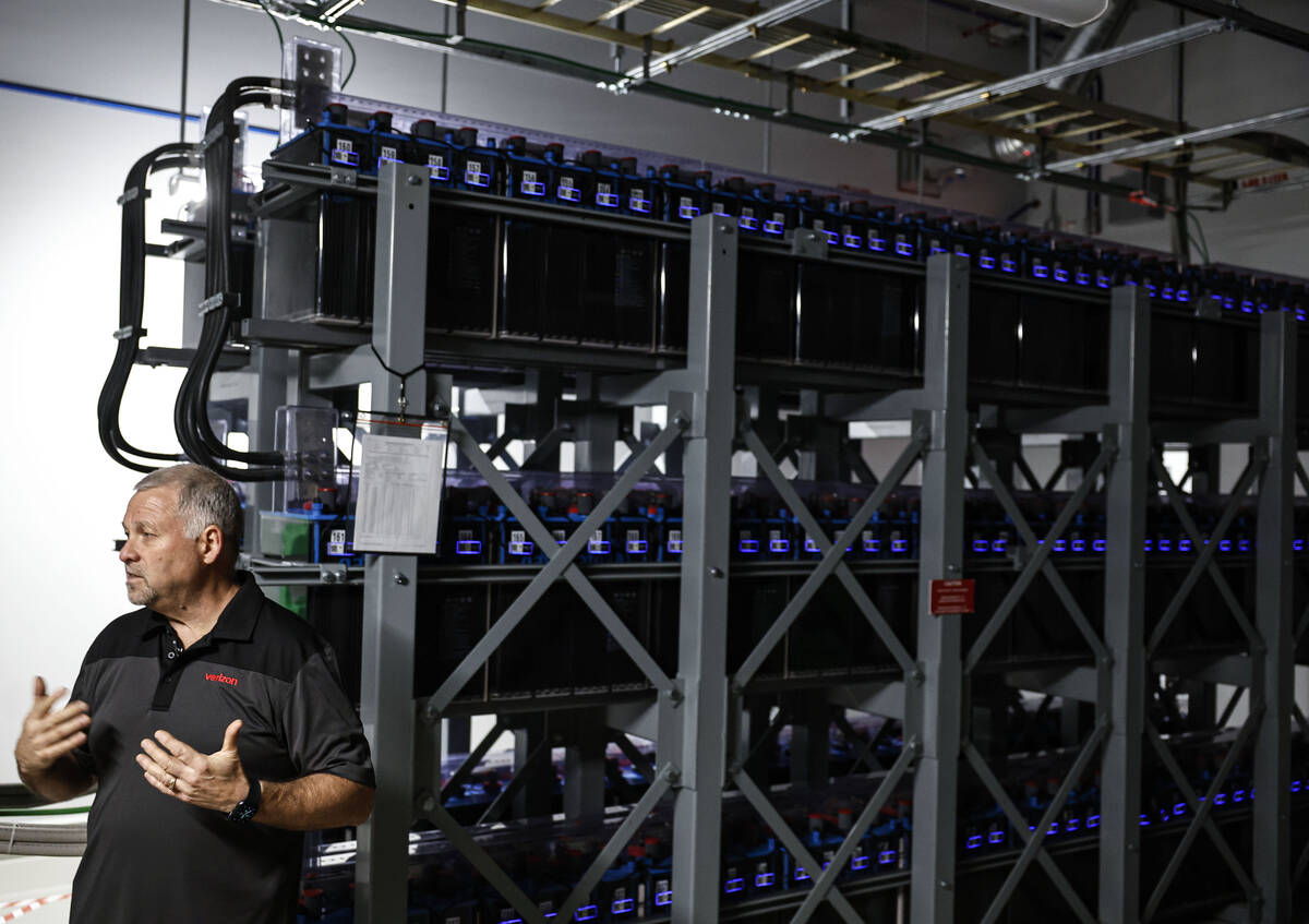 Dave Nelson, senior director of operations, points out features of large rows of battery stora ...