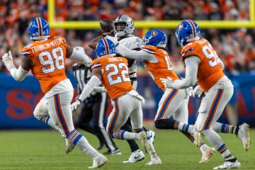 Raiders quarterback Geno Smith (7) is swarmed by Denver Broncos defenders during the second hal ...