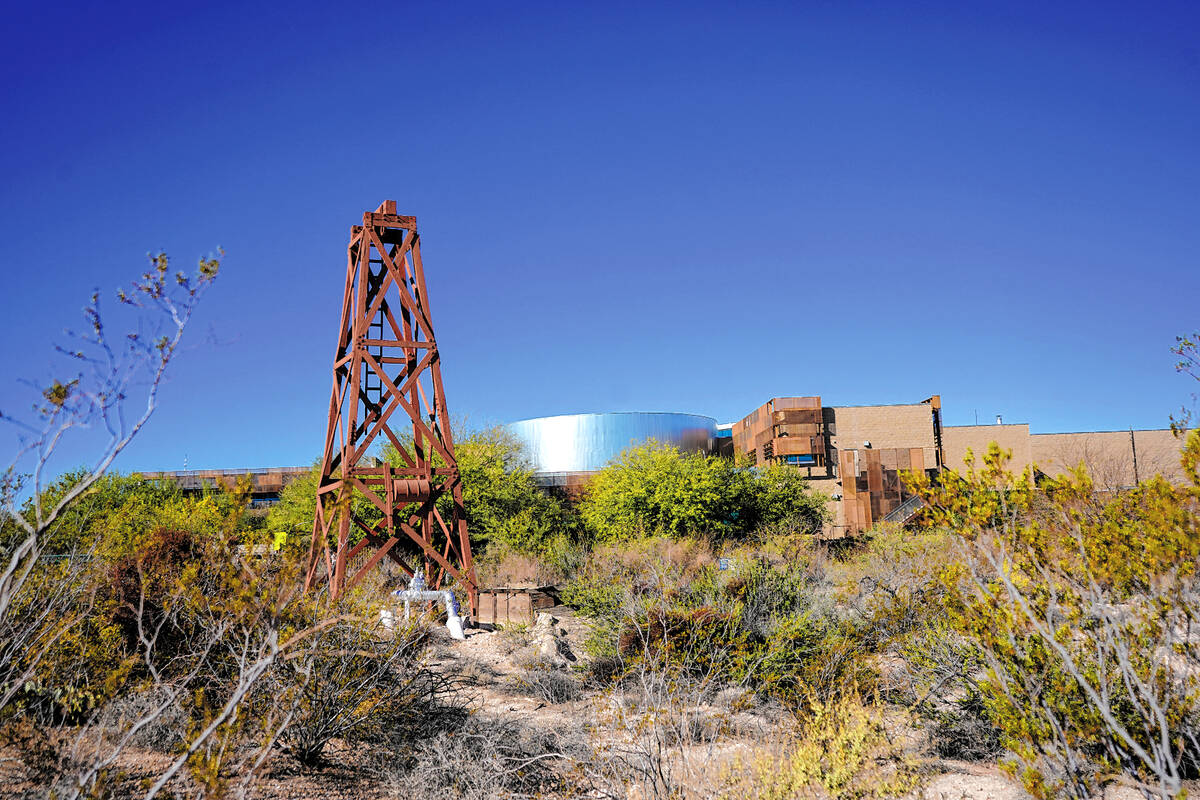 A historic well derrick stands in contrast to the modern architecture of the Springs Preserve, ...