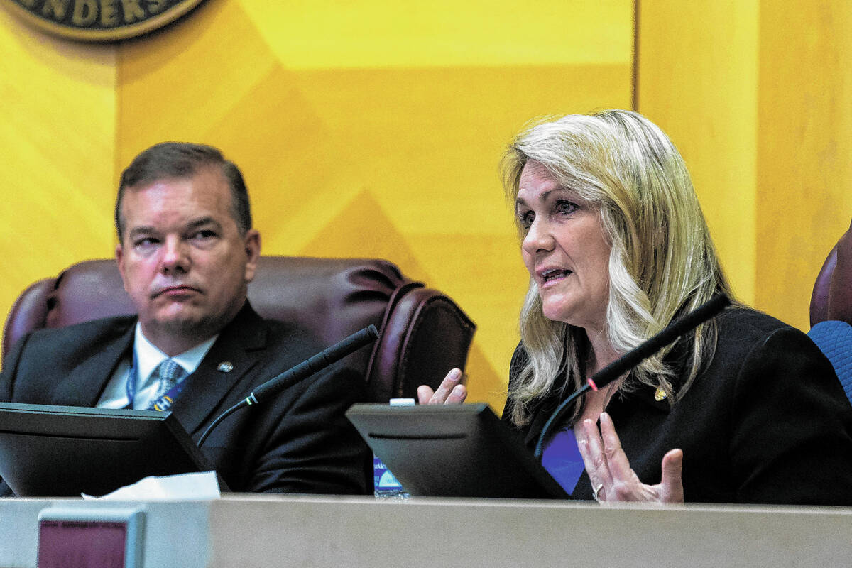 Council member Carrie Cox speaks with Jim Seebock nearby during a Henderson City Council meetin ...