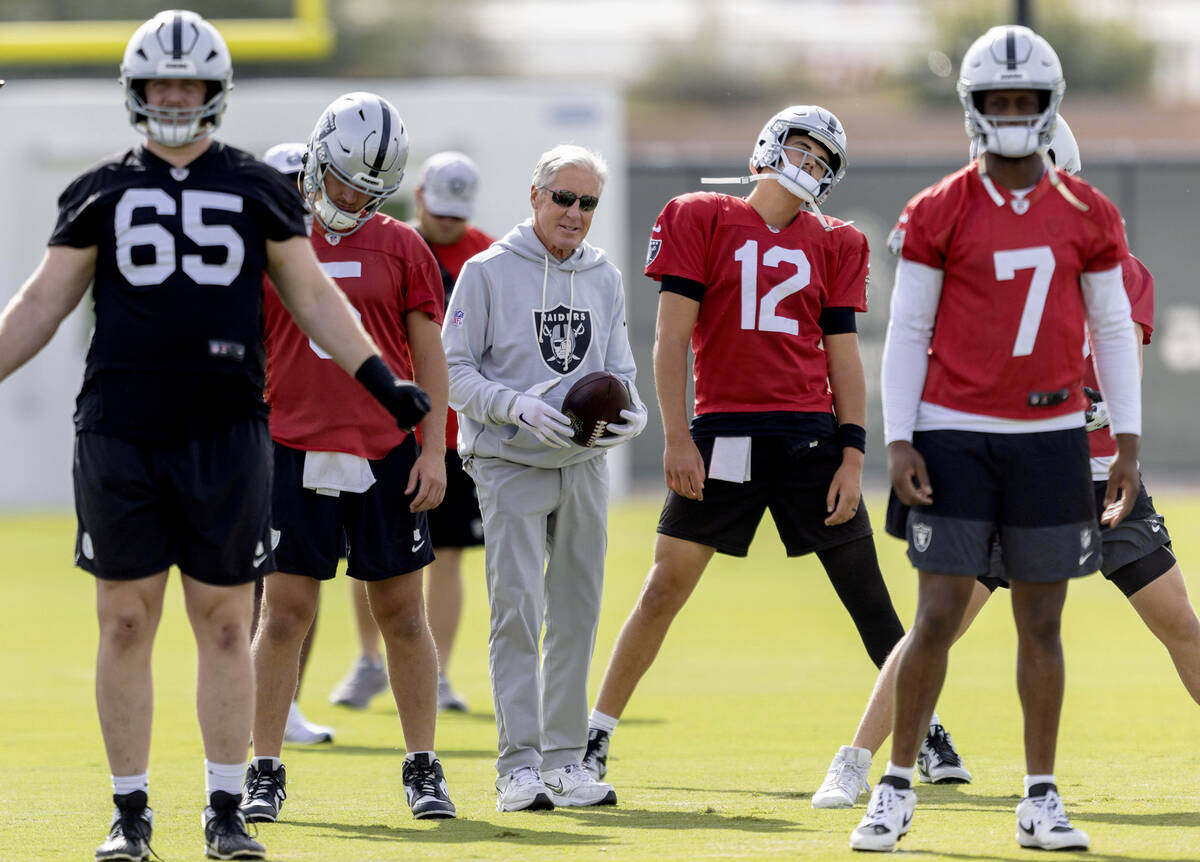 Raiders head coach Pete Carroll walks through warm ups with guard Alex Cappa (65), quarterback ...