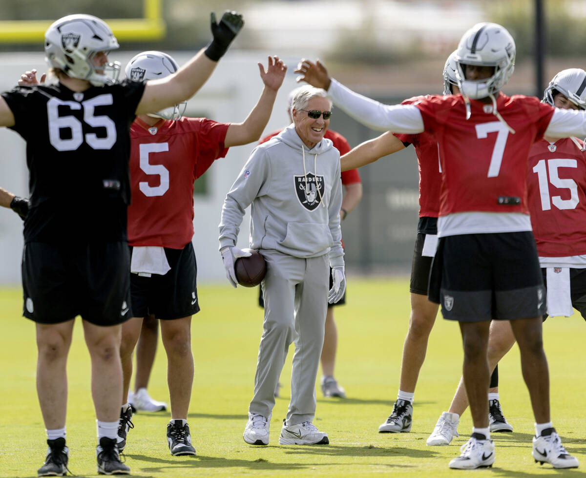 Raiders head coach Pete Carroll walks through warm ups with guard Alex Cappa (65), quarterback ...