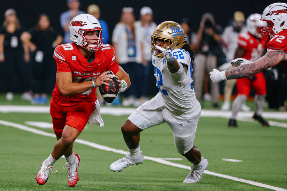 UNLV quarterback Anthony Colandrea (10) looks to run around UCLA defensive lineman Kechaun Benn ...
