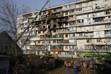 Rescuers work on the scene of a building damaged after a Russian attack in Kyiv, Ukraine, on Fr ...