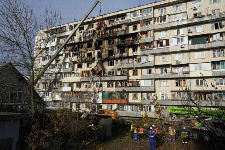 Rescuers work on the scene of a building damaged after a Russian attack in Kyiv, Ukraine, on Fr ...
