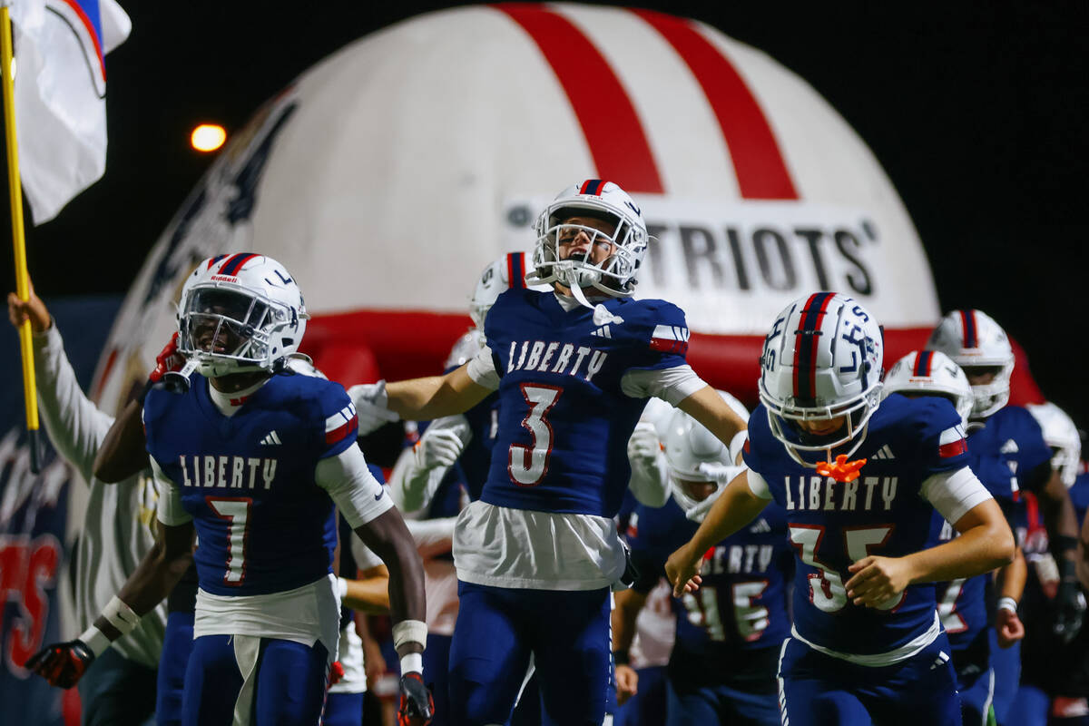 Liberty teammates Ameche Baldwin (7), Brody Gavin(3) and Gunnar Massenburg (35) run out before ...