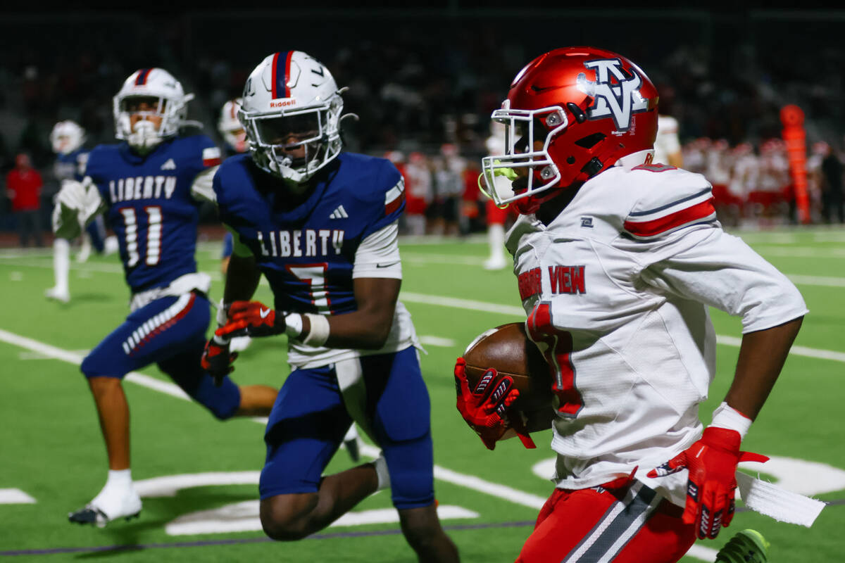 Arbor View running back Kamareion Bell (0) runs upfield with Liberty’s Ameche Baldwin (7 ...
