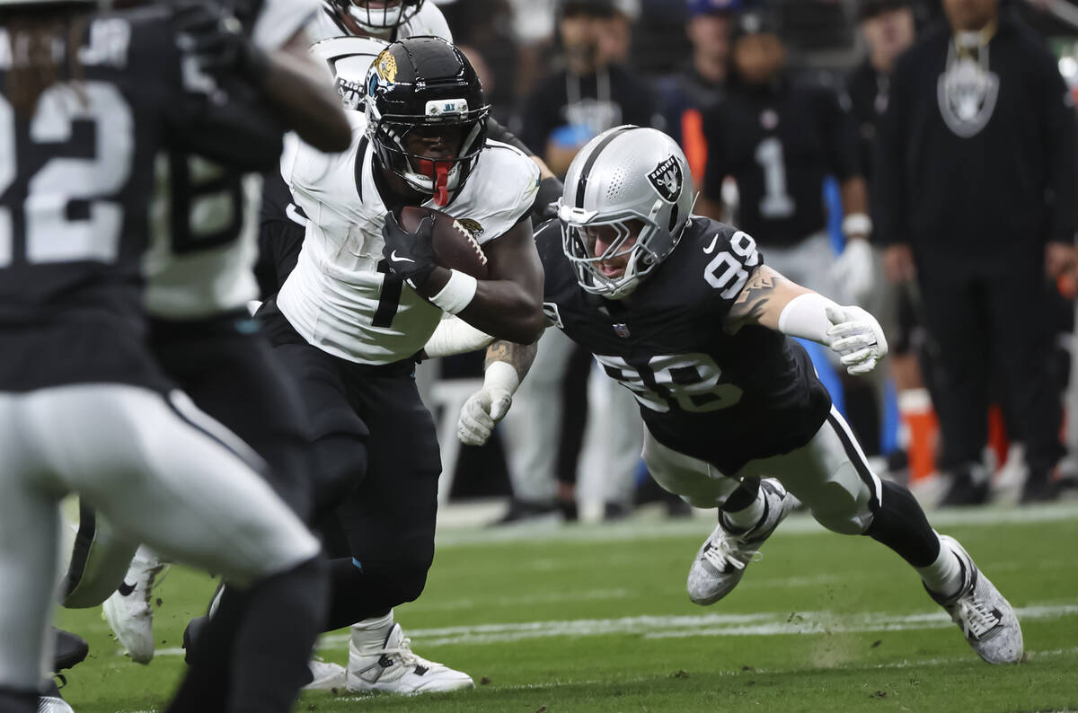 Raiders defensive end Maxx Crosby (98) tries to tackle Jacksonville Jaguars running back Travis ...