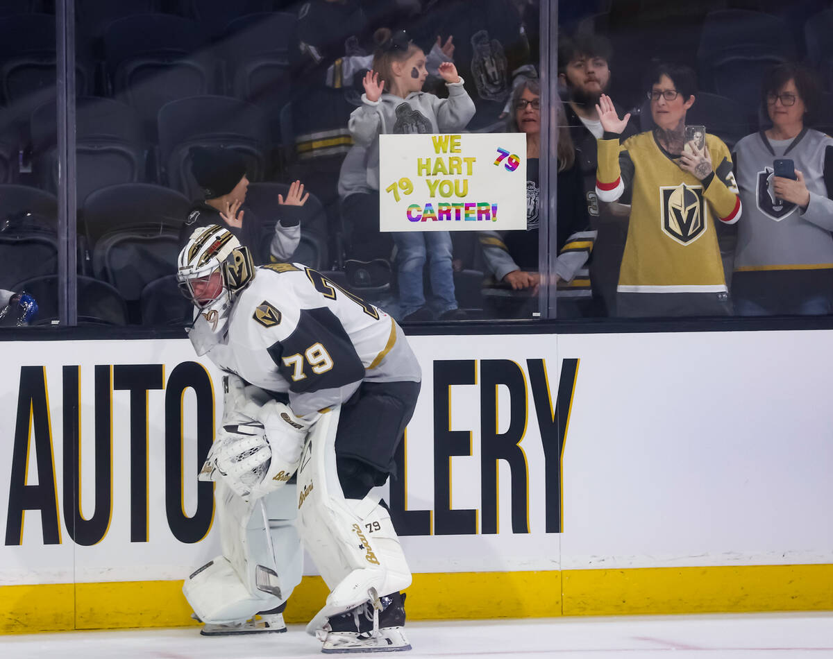 Silver Knights goaltender Carter Hart (79) warms up as a young fan holds up a sign in support b ...
