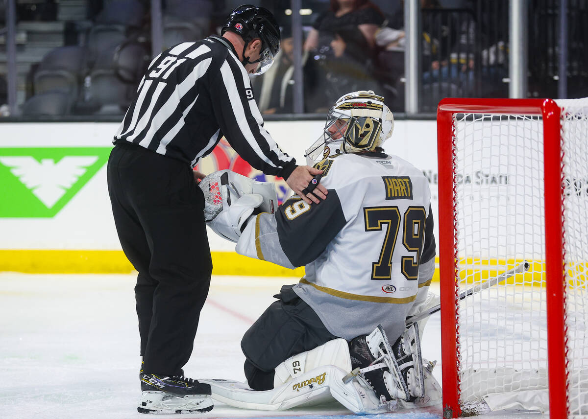Silver Knights goaltender Carter Hart (79) hands the puck to AHL linesman Logan Wescott (91) du ...