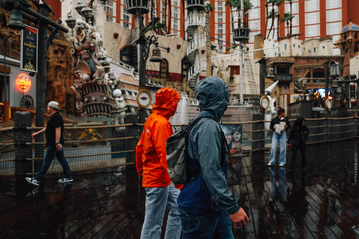 Pedestrians take cover from the rain on the Strip Saturday, Nov. 15, 2025, in Las Vegas. (Madel ...