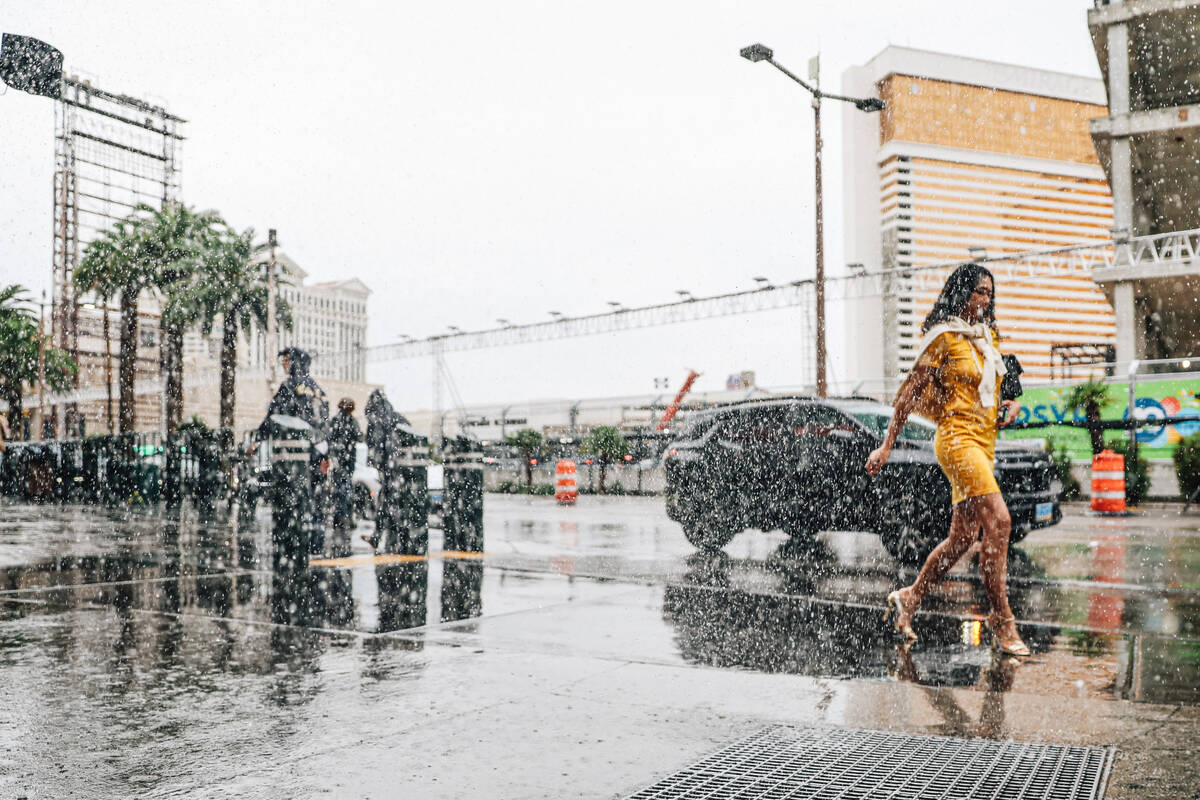 Pedestrians take cover from the rain on the Strip Saturday, Nov. 15, 2025, in Las Vegas. (Madel ...