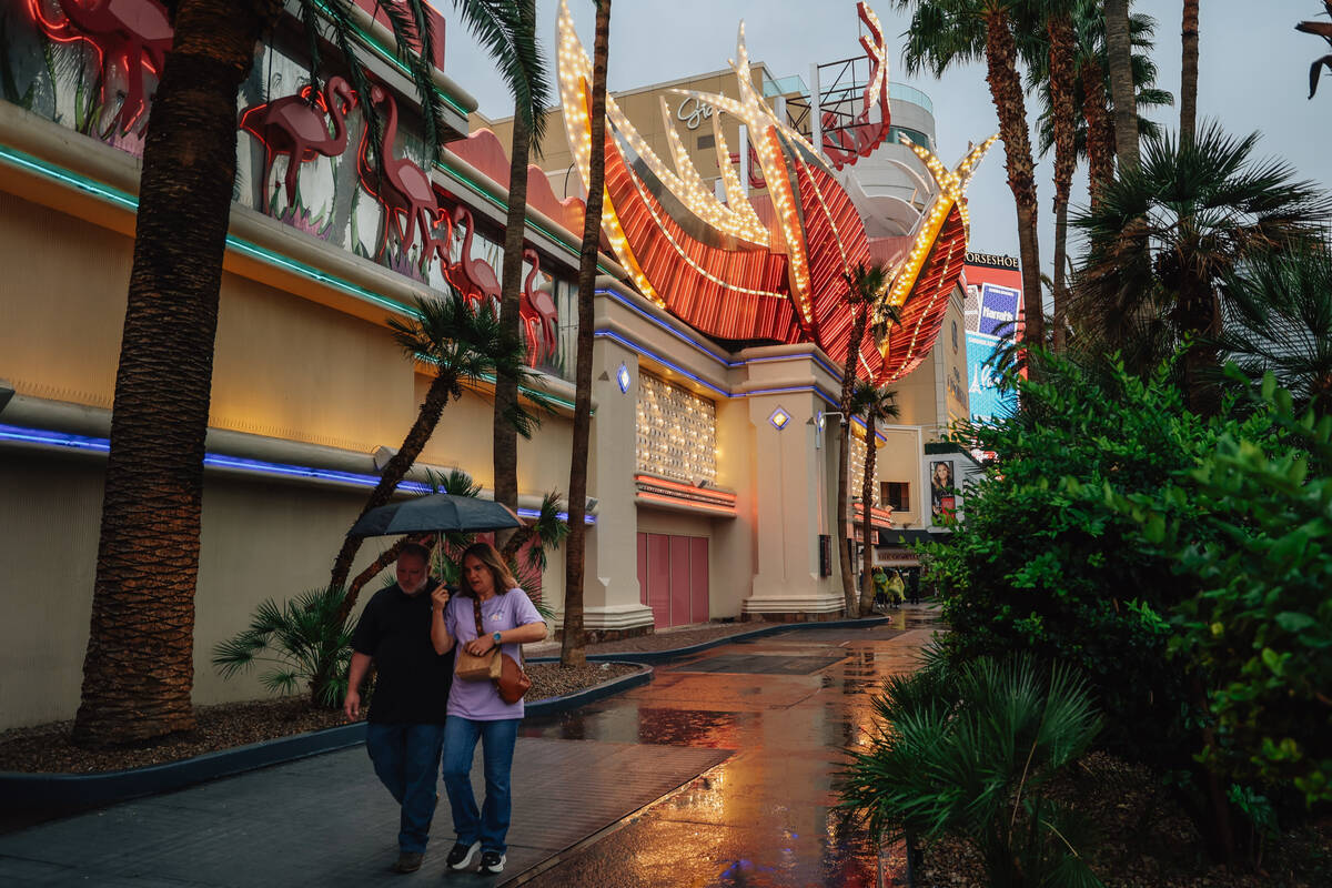 Pedestrians take cover from the rain on the Strip Saturday, Nov. 15, 2025, in Las Vegas. (Madel ...