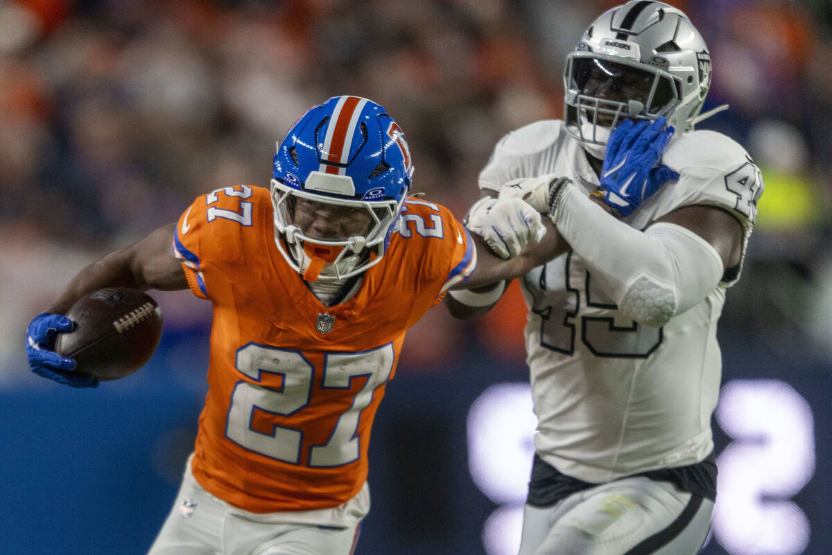 Raiders linebacker Devin White (45) is stiff armed by Denver Broncos running back J.K. Dobbins ...