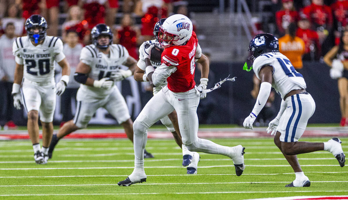 UNLV wide receiver Troy Omeire (0) secures a long pass and breaks upfield past Utah State Aggie ...