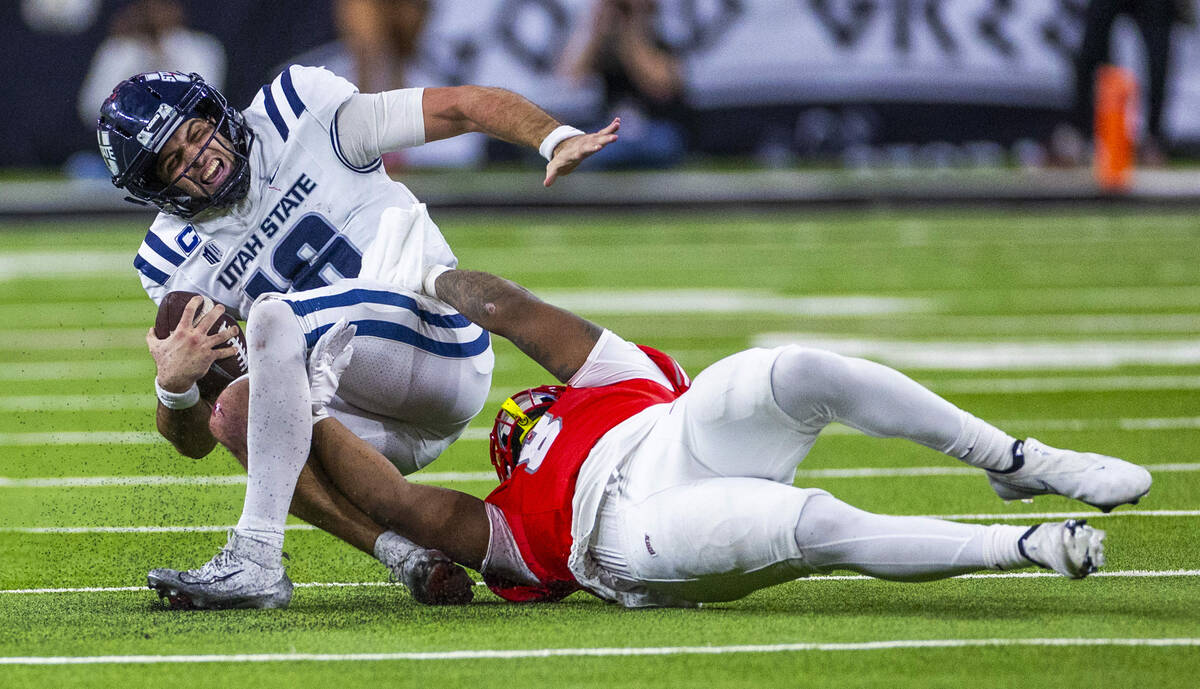 Utah State Aggies quarterback Bryson Barnes (16) is pulled down on a run by UNLV linebacker Mar ...