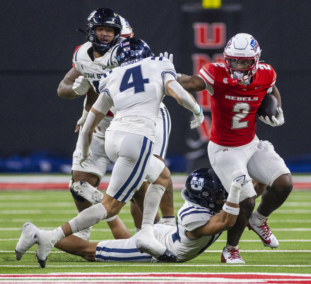 UNLV running back Keyvone Lee (2) battles for yards against Utah State Aggies safety Brevin Ham ...