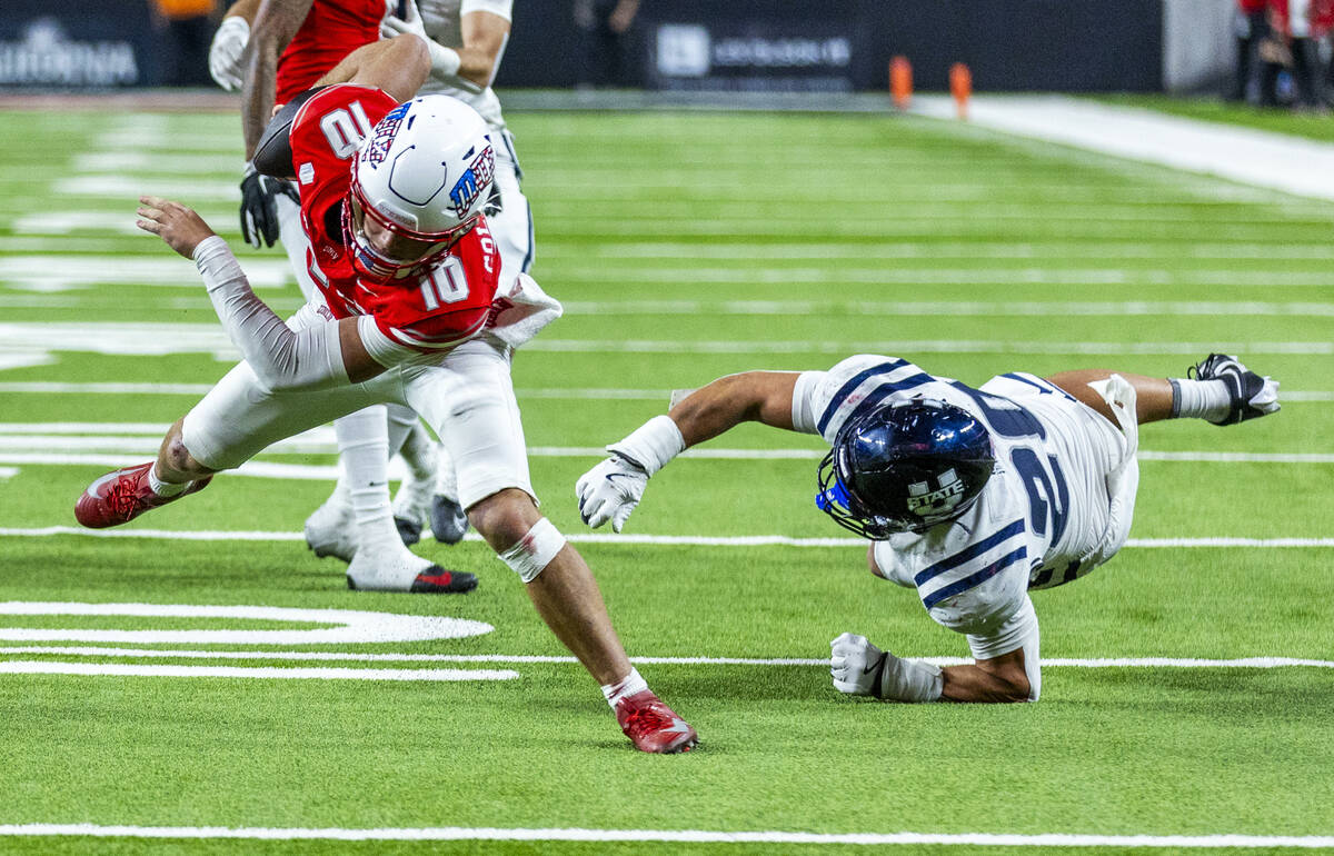 UNLV quarterback Anthony Colandrea (10) shakes off a tackle attempt by Utah State Aggies lineba ...