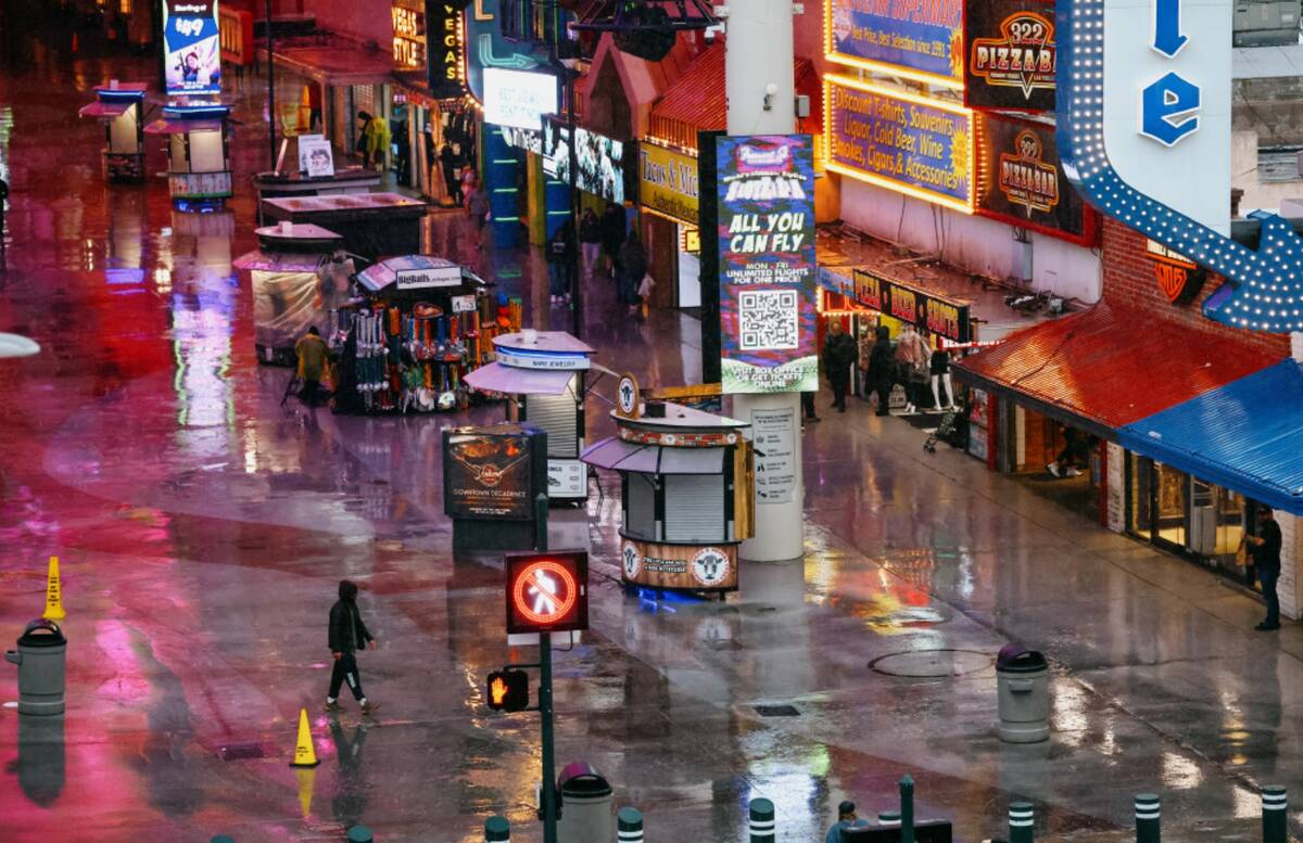 A pedestrian walks in the rain on Tuesday, Nov. 18, 2025 at the Fremont Street Experience in La ...
