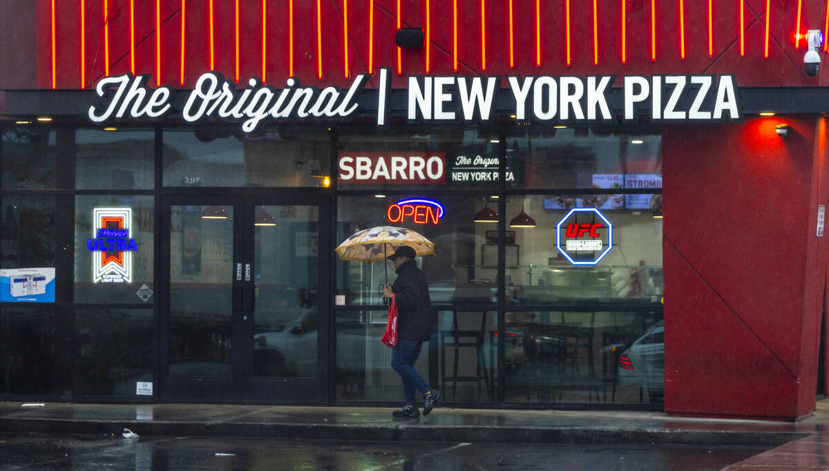 A person with an umbrella walks past the Sbarro restaurant off Paradise Road on Tuesday, Nov. 1 ...